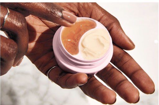 A closeup look at a person holding a cream and using other hand to take it out.