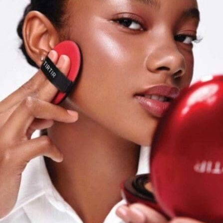 Woman applying makeup with red puff.