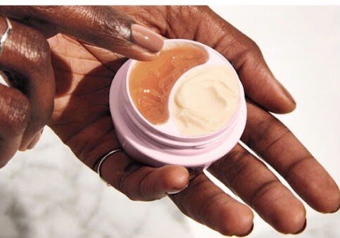 A closeup look at a person holding a cream and using other hand to take it out.